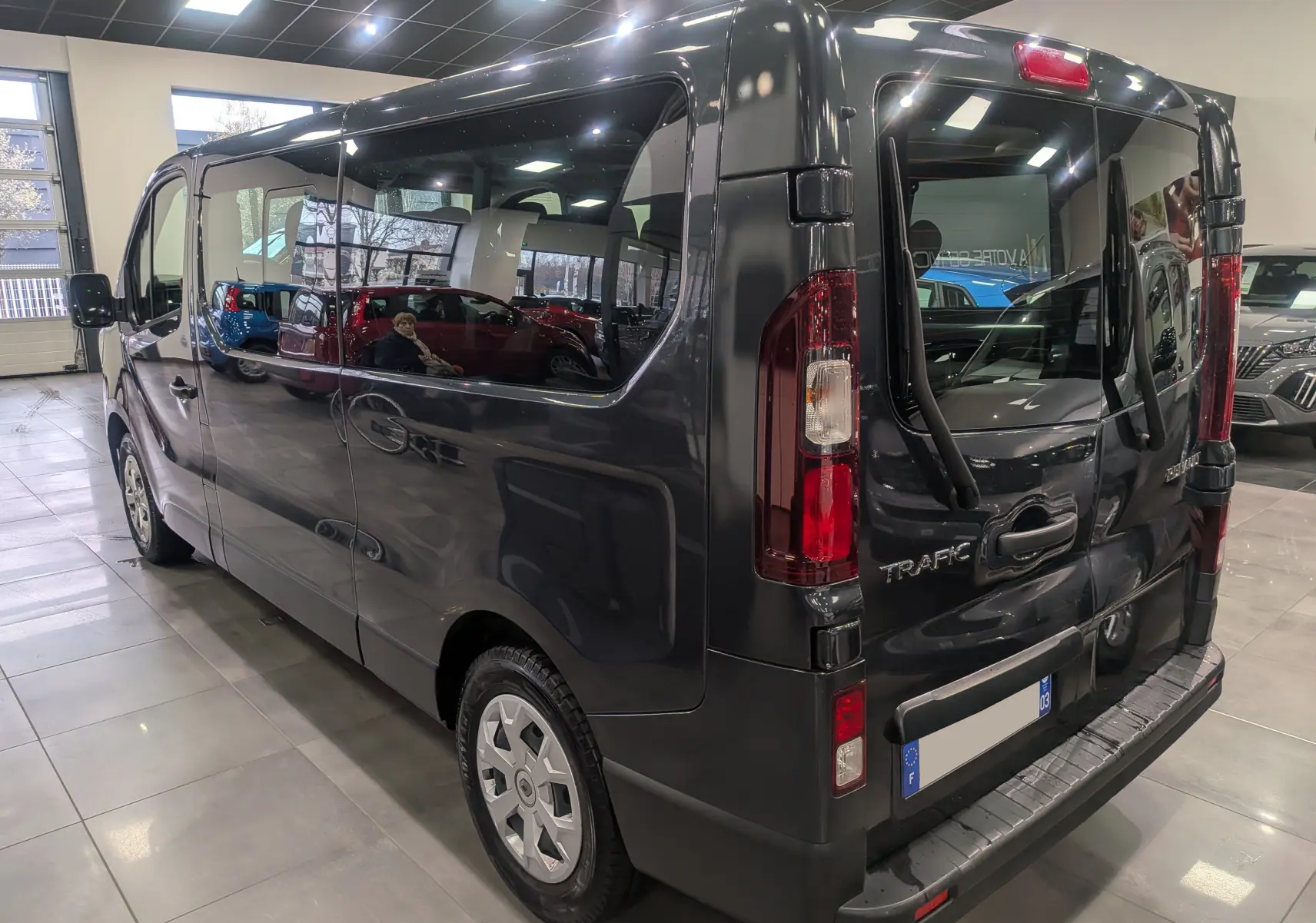 Vue 3/4 arrière droite du Renault Trafic Combi gris Comète, mettant en valeur ses grandes vitres latérales et portes arrière vitrées.