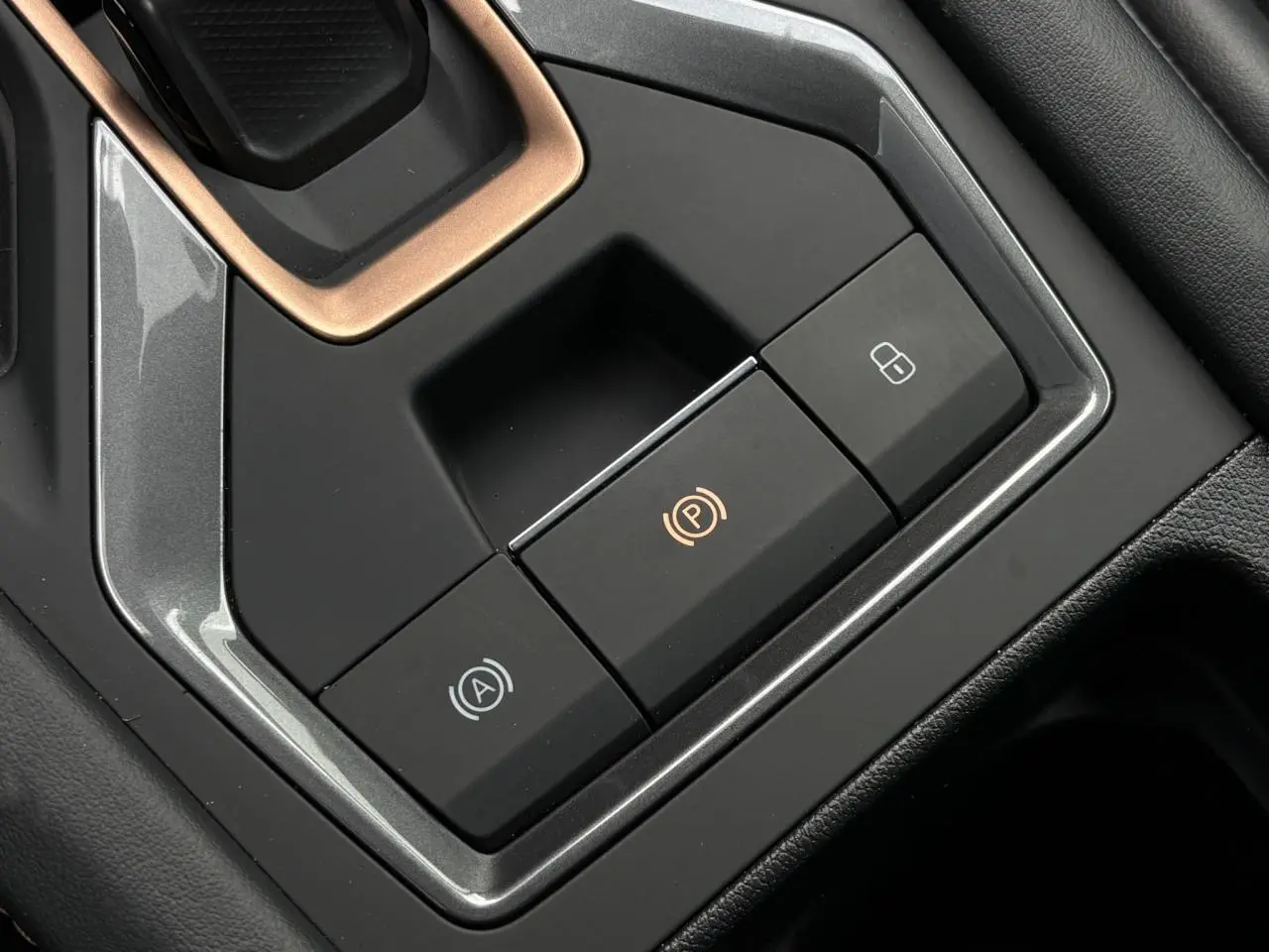 Gros plan sur les commandes de frein à main électronique et verrouillage central dans l’habitacle noir du CUPRA Leon 2025.