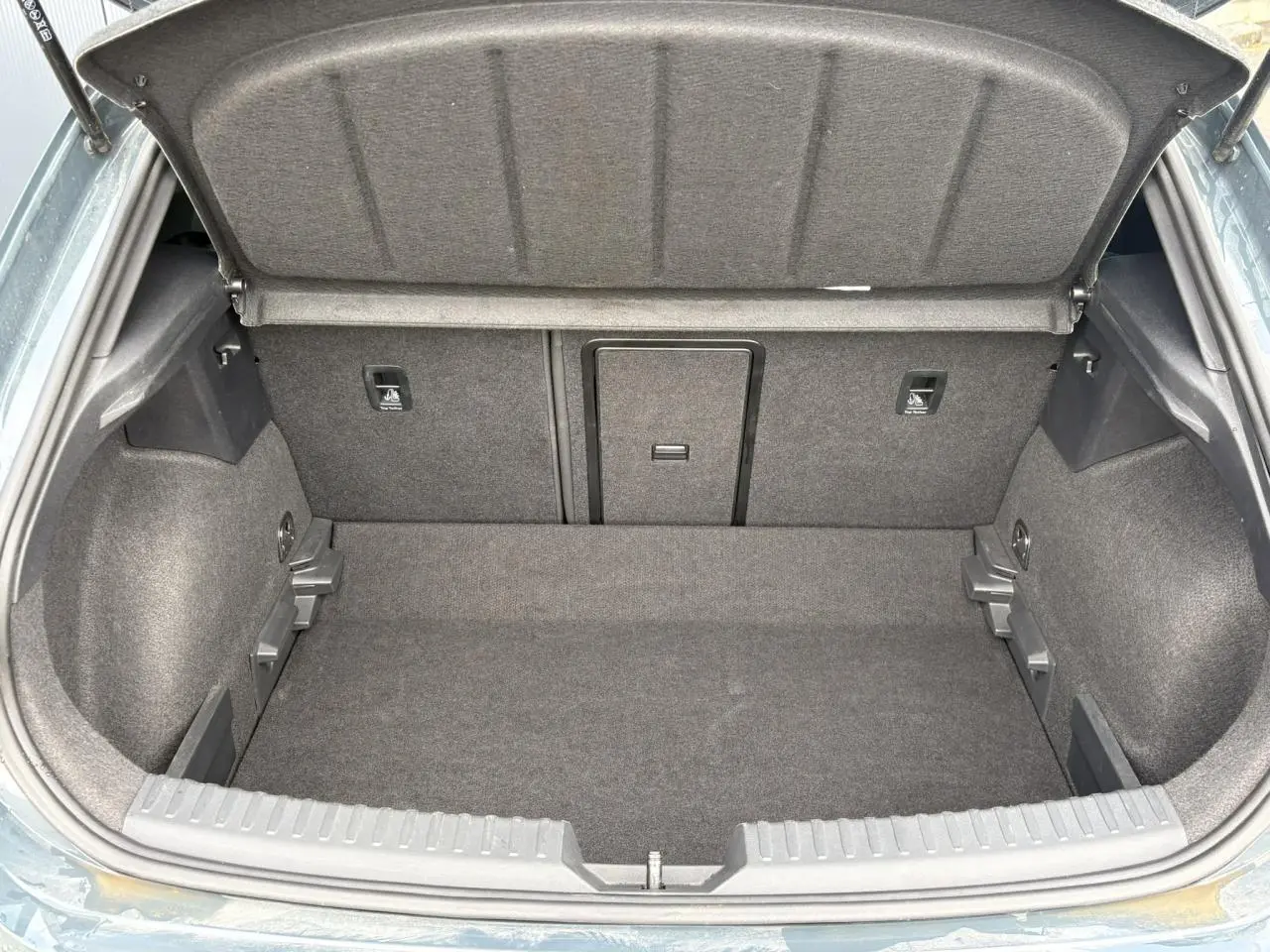 Coffre ouvert vu de l'arrière d'une CUPRA Leon 1.5 e-TSI 150 Bleu Fjord, intérieur de coffre en tissu gris.