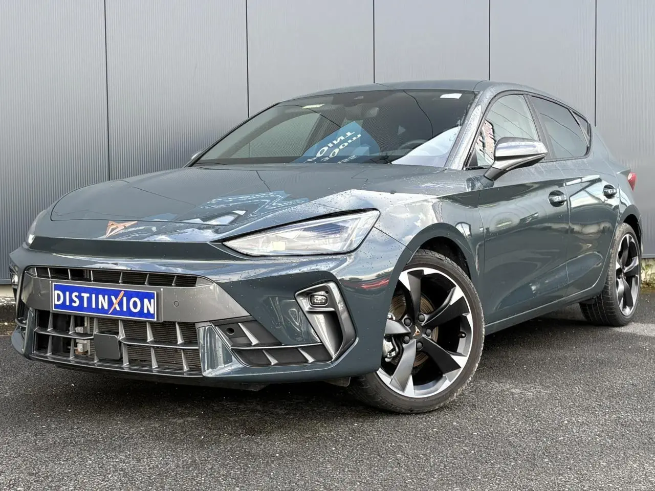 Vue 3/4 avant d'une CUPRA Leon 1.5 e-TSI 150 bleu Fjord avec jantes alliage 18'' et signature lumineuse Tri-LED.