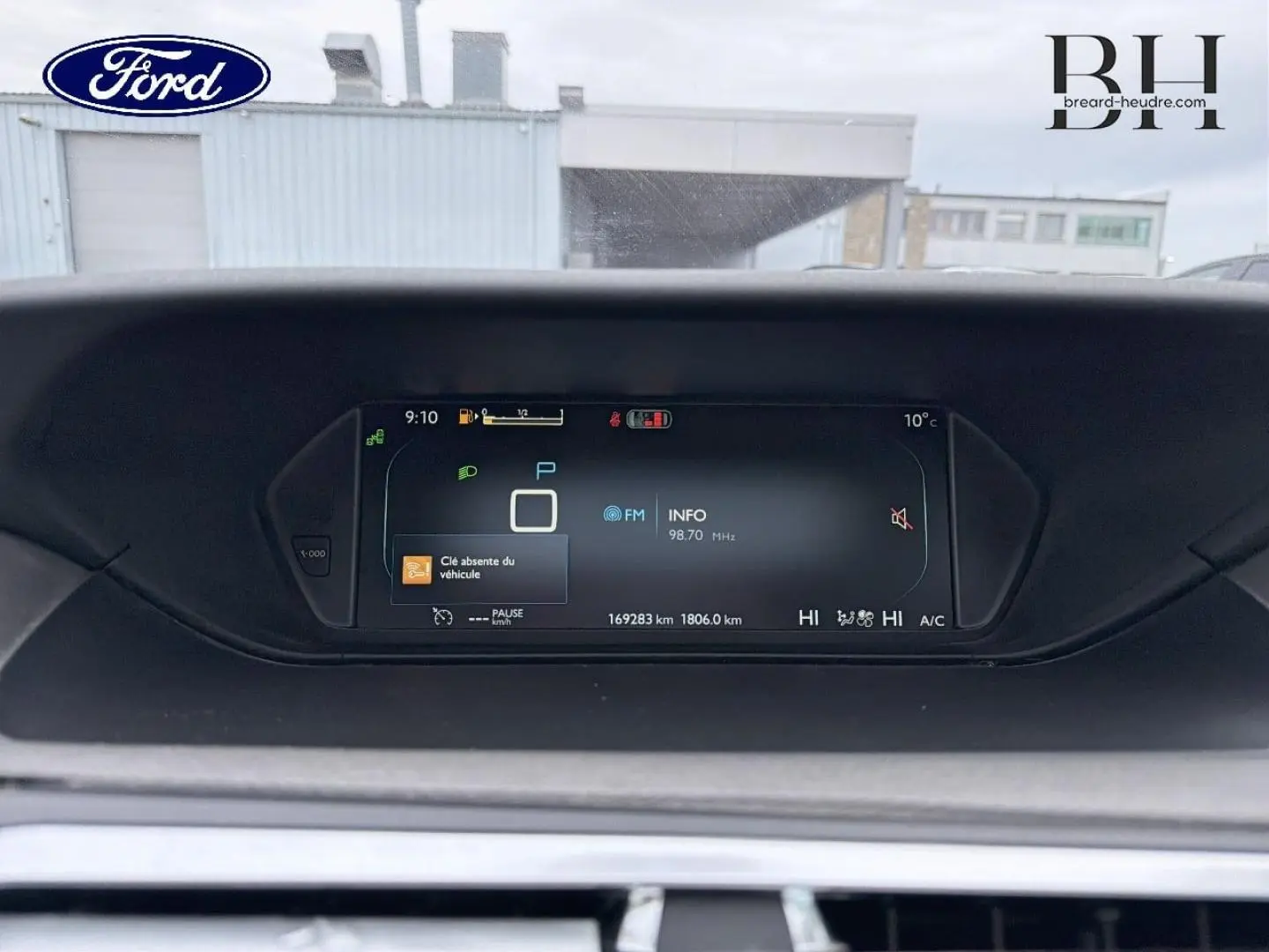 Tableau de bord numérique d'une Citroën C4 Picasso gris Shark, affichant la vitesse et les informations radio.