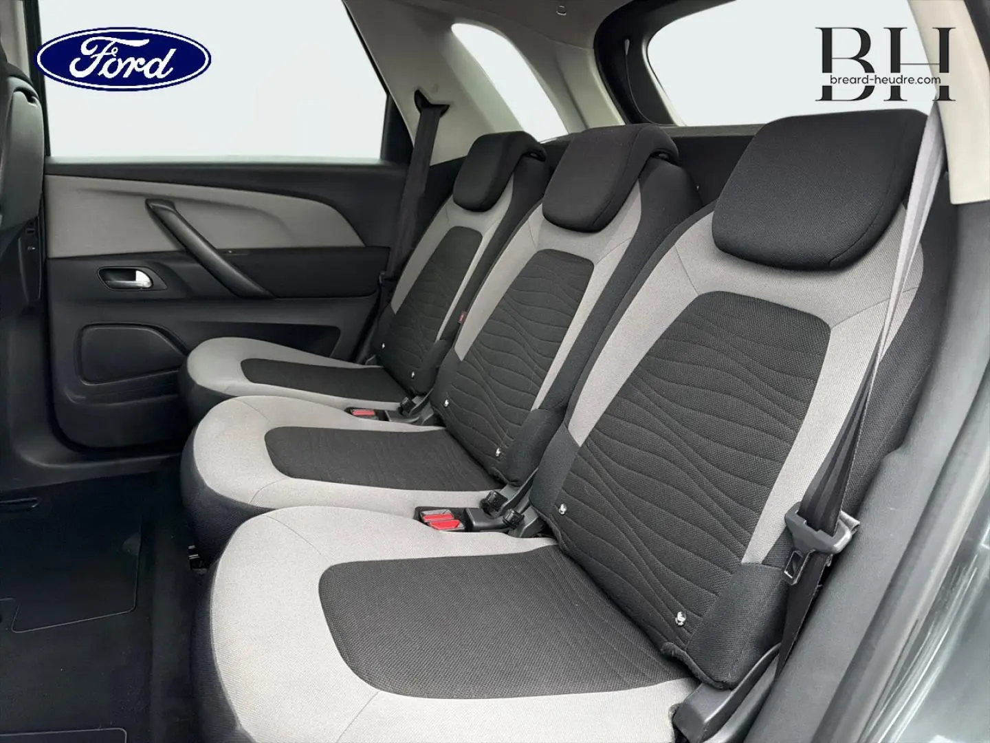 Vue latérale des trois sièges individuels arrière gris et noirs du Citroën C4 Picasso, avec ceintures de sécurité visibles.