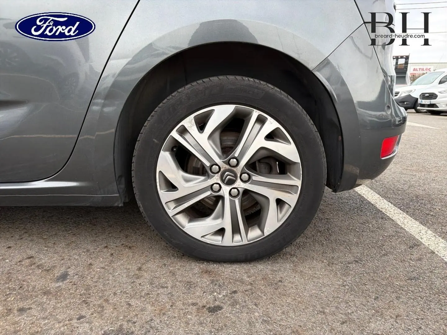 Gros plan sur la roue arrière droite avec jante alu gris argent du Citroën C4 Picasso gris Shark.