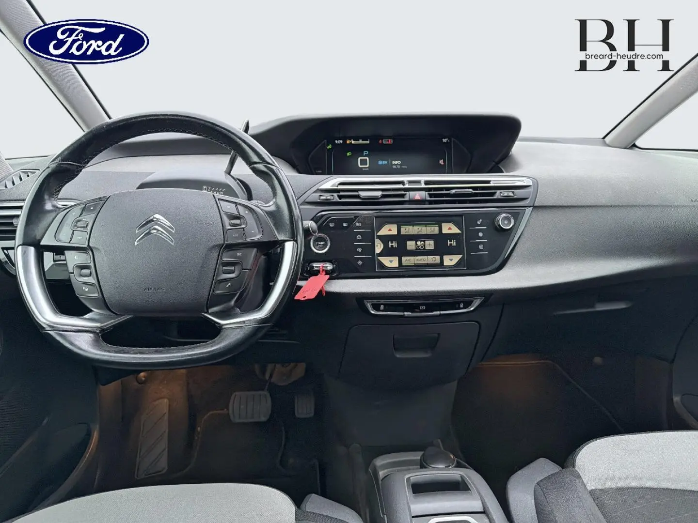 Vue intérieure frontale du tableau de bord et volant noir d'une Citroën C4 Picasso gris Shark de 2016.