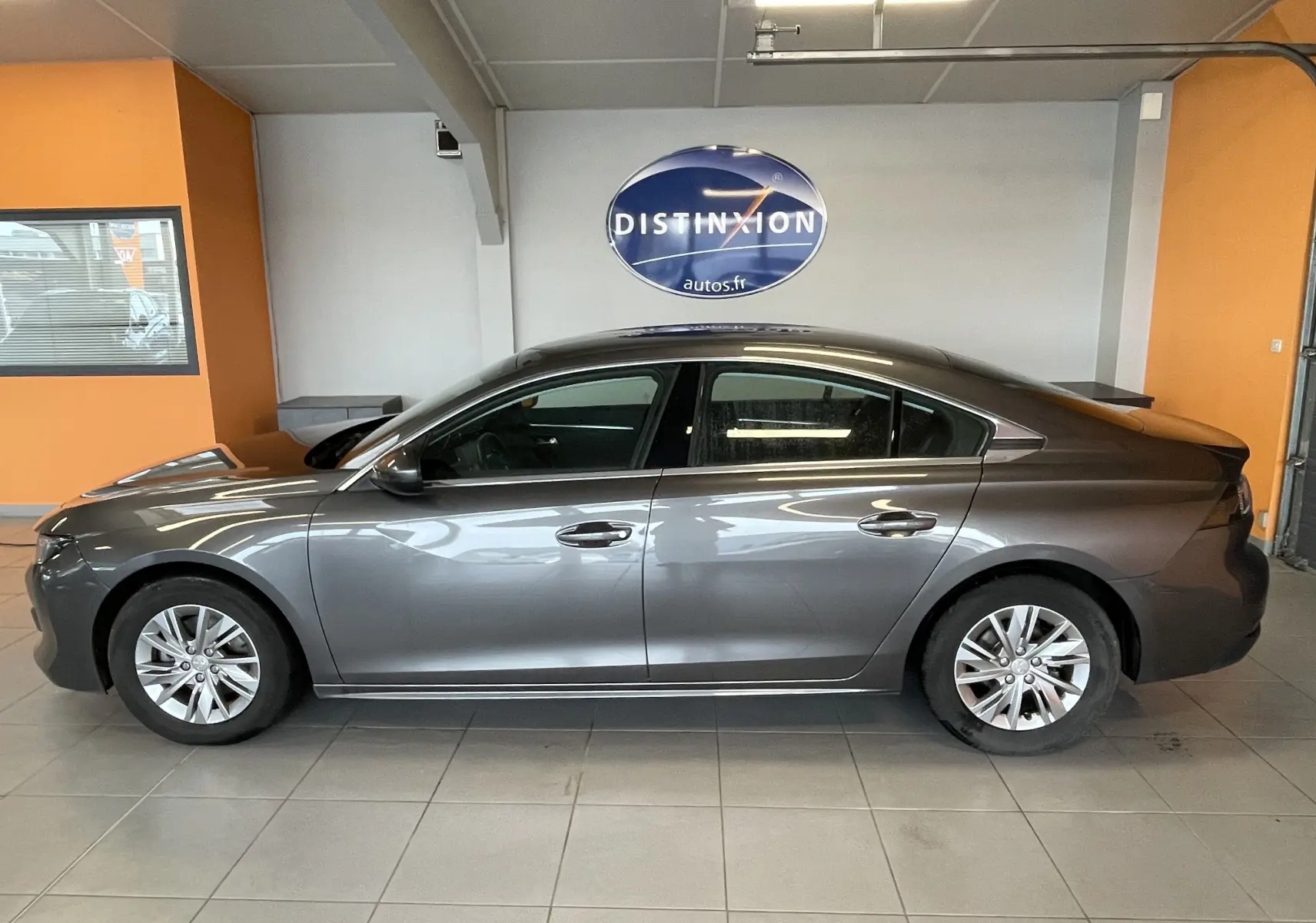 Profil côté gauche d'une Peugeot 508 gris platinium de 2021, berline élégante avec jantes alliage et vitres teintées.