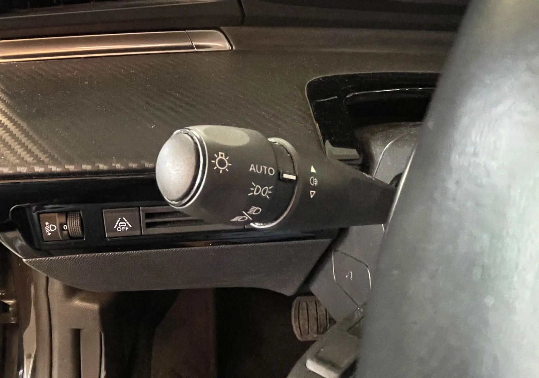 Gros plan sur la commande d'éclairage automatique à gauche du volant dans l'habitacle du Peugeot 508 gris platinium.