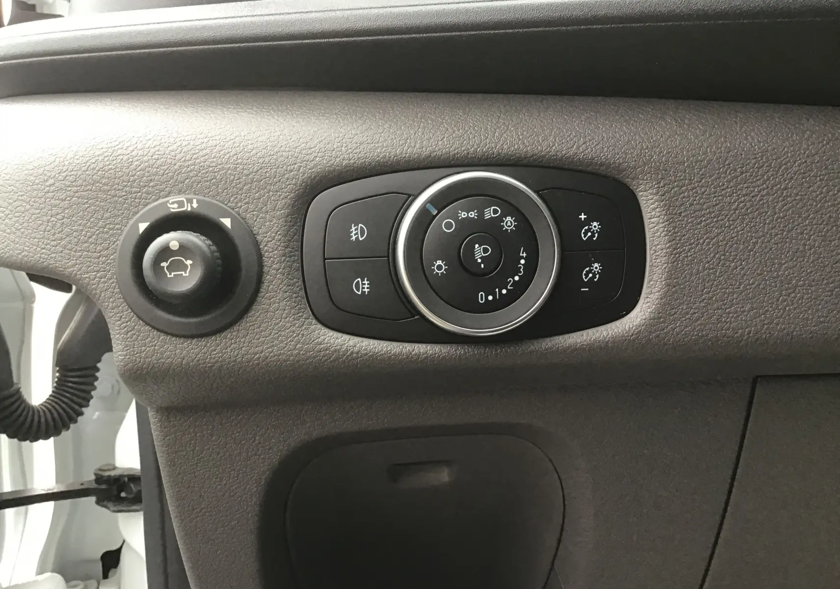 Gros plan sur les commandes d'éclairage et réglage des rétroviseurs du Ford Transit Chassis Cabine blanc, intérieur côté gauche.