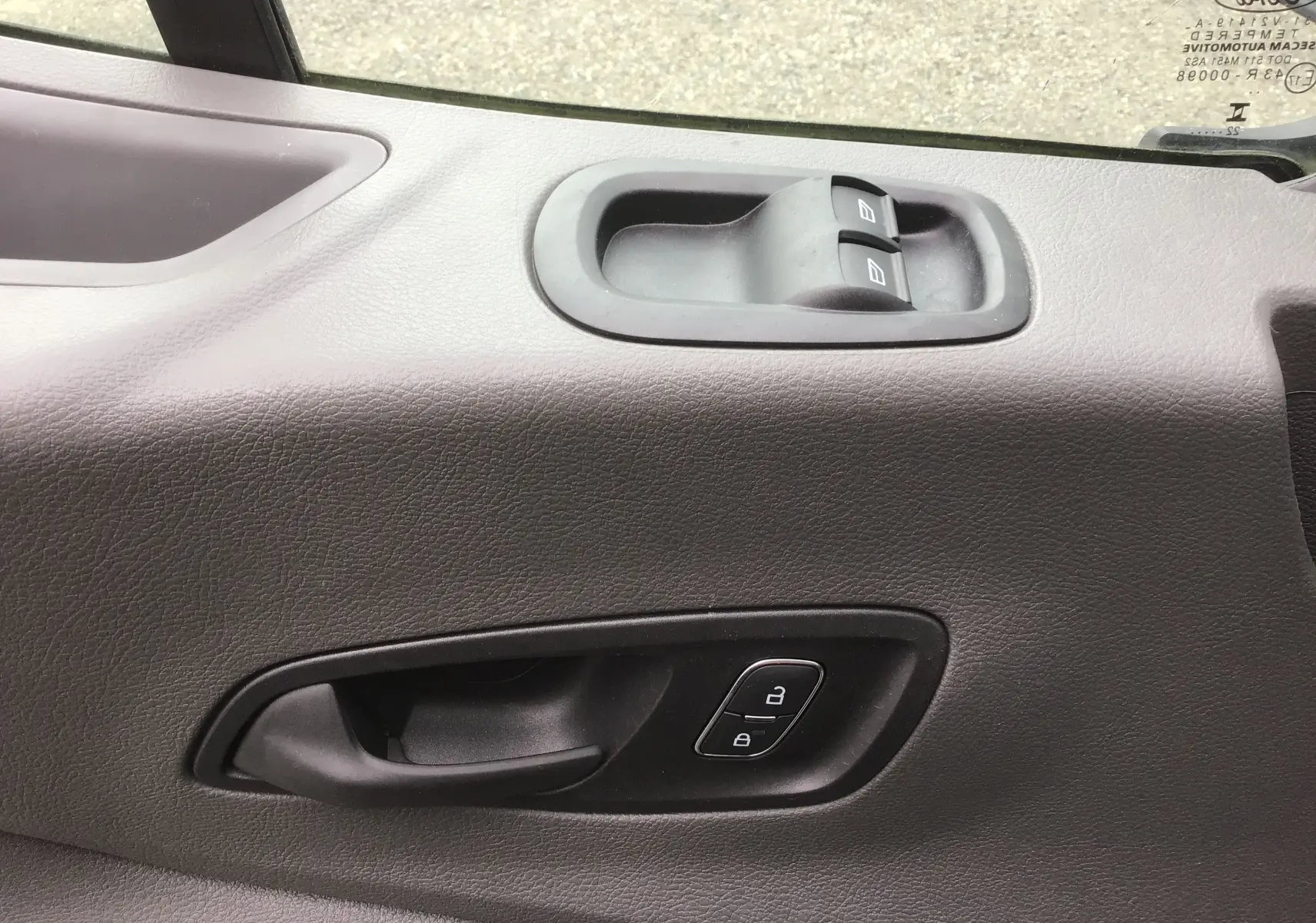 Gros plan sur la poignée intérieure et les commandes de lève-vitres côté conducteur d'un Ford Transit blanc 2024.