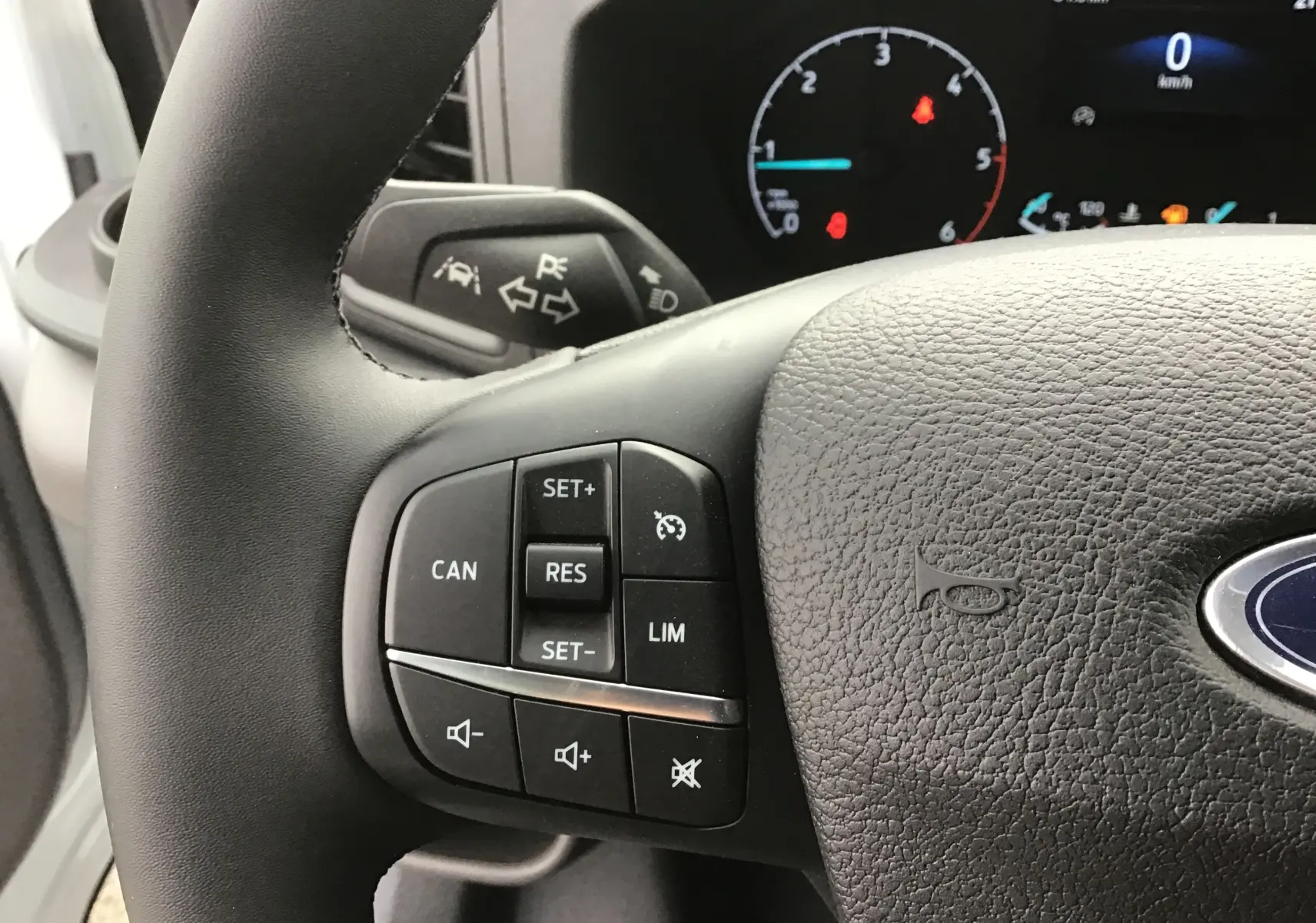 Gros plan sur le volant noir du Ford Transit Chassis Cabine 2024 avec commandes de régulateur de vitesse et logo Ford visible.