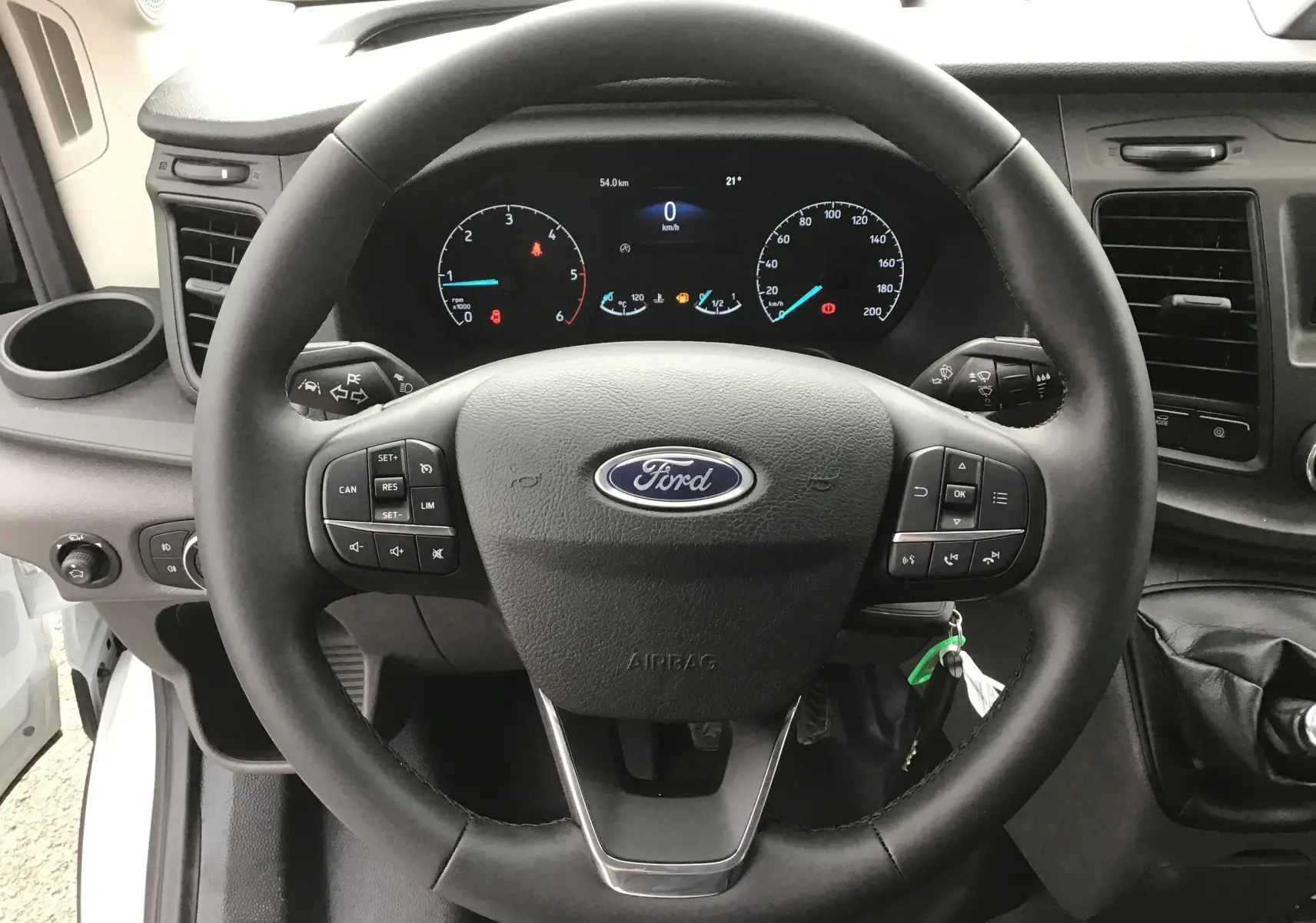 Vue rapprochée du volant Ford du Transit Châssis Cabine blanc 2024 avec commandes intégrées et tableau de bord digital.