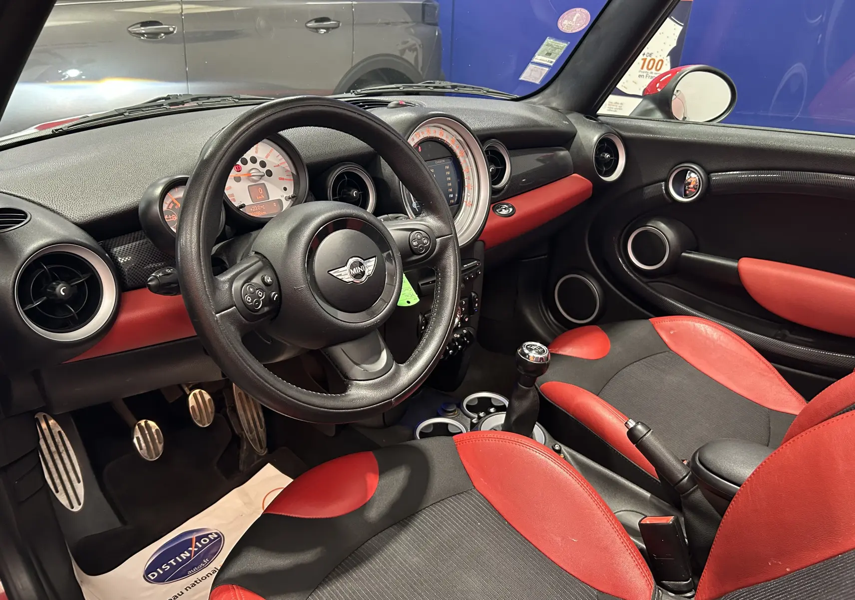 Intérieur avant droit d'une MINI Cabriolet Cooper S rouge de 2012, avec sièges et tableau de bord rouge et noir, volant multifonction.