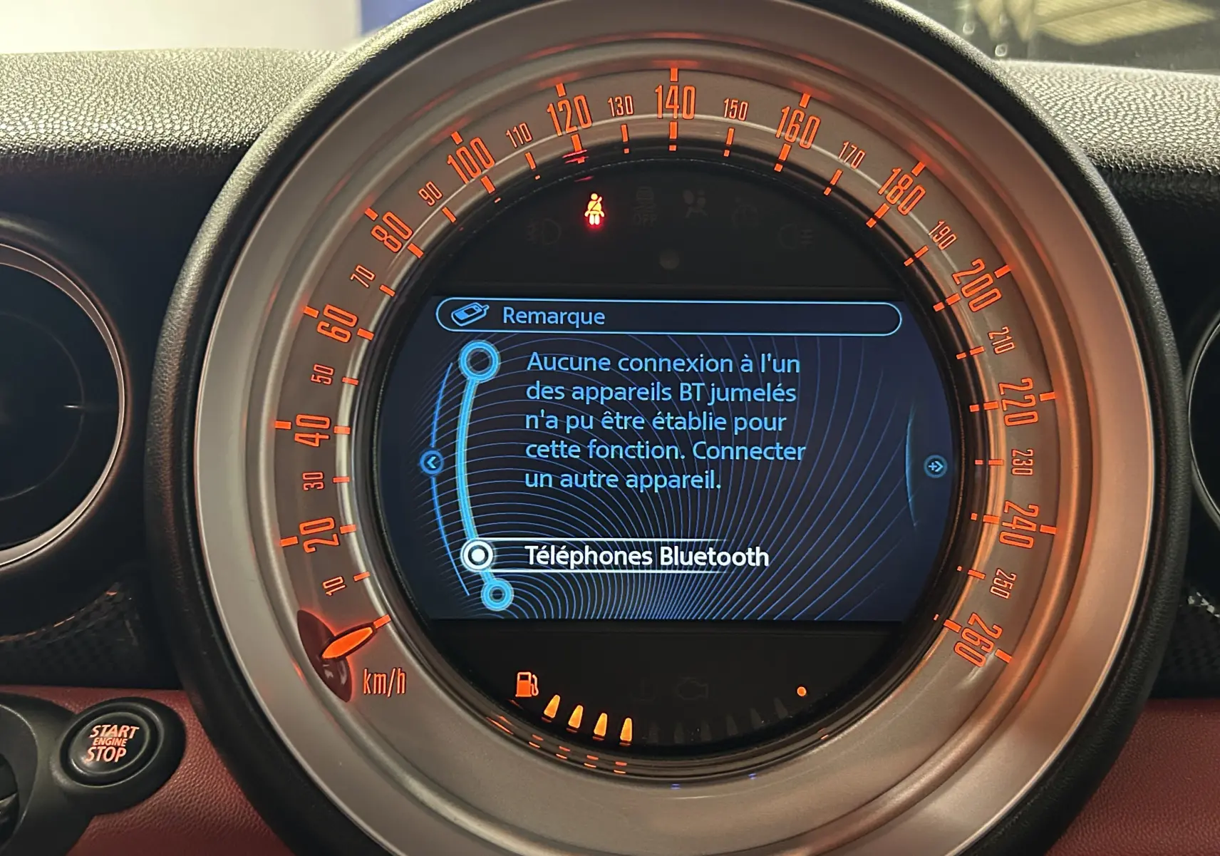 Gros plan sur le tableau de bord du MINI Cabriolet Cooper S rouge, affichant l'écran central avec message Bluetooth.