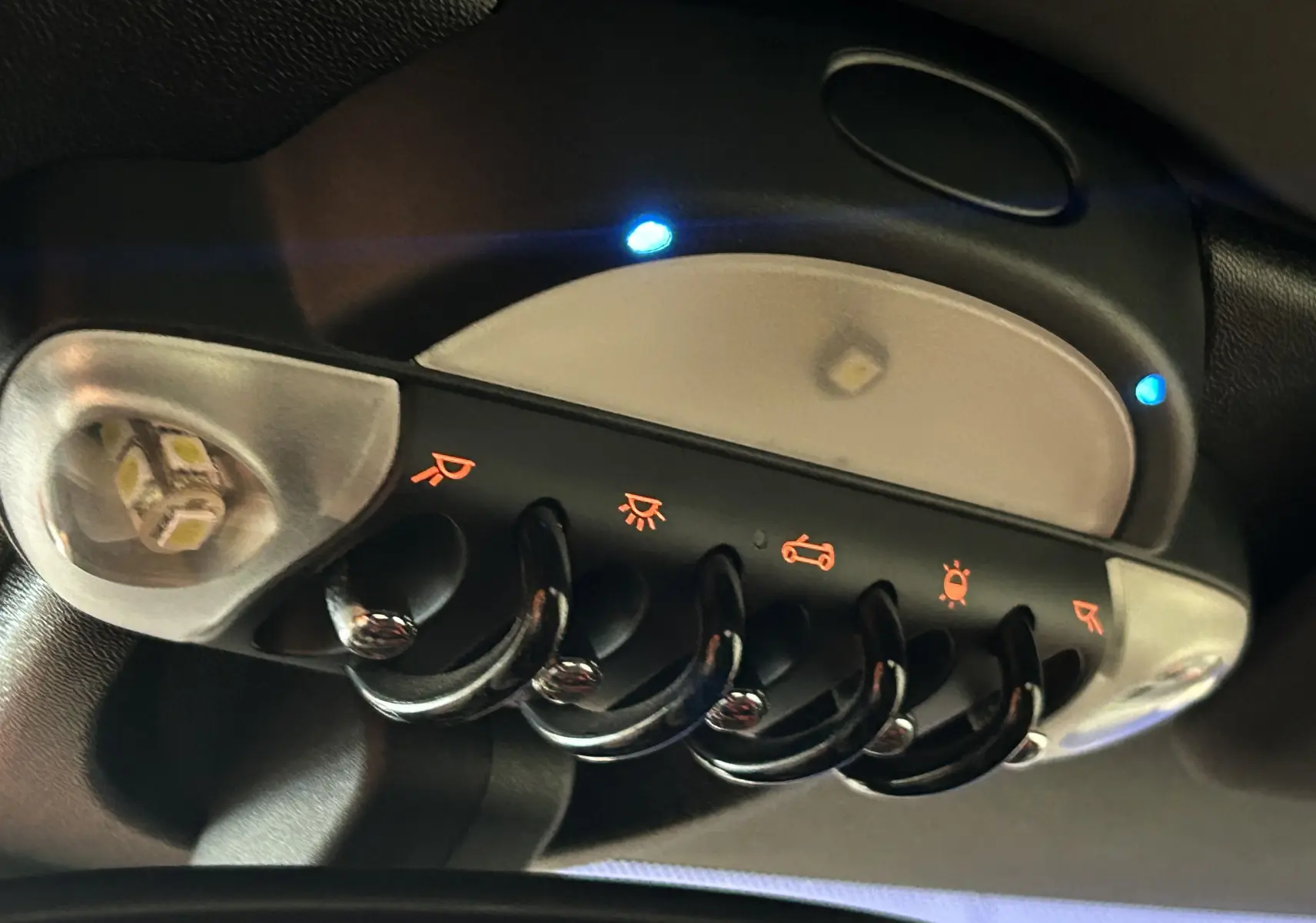 Gros plan sur les boutons de commande de vitres électriques dans l'habitacle noir d'une MINI Cabriolet Cooper S rouge 2012.