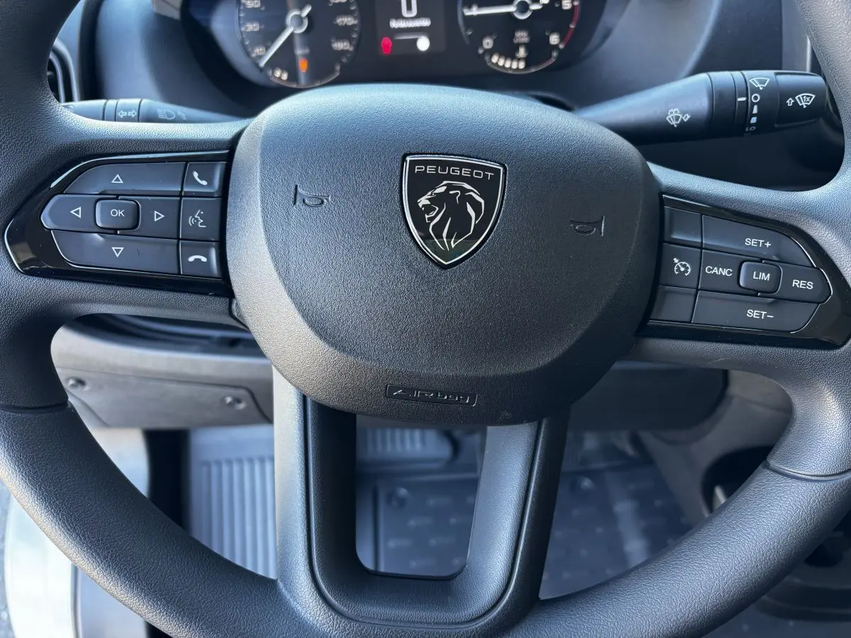 Gros plan sur le volant noir multifonctions du Peugeot Boxer Fourgon 2025, avec logo lion central visible.