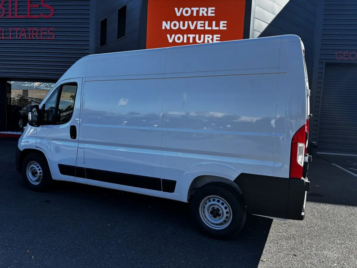 Vue latérale droite d'un utilitaire Peugeot Boxer Fourgon blanc, avec cloison pleine et jantes acier simples.