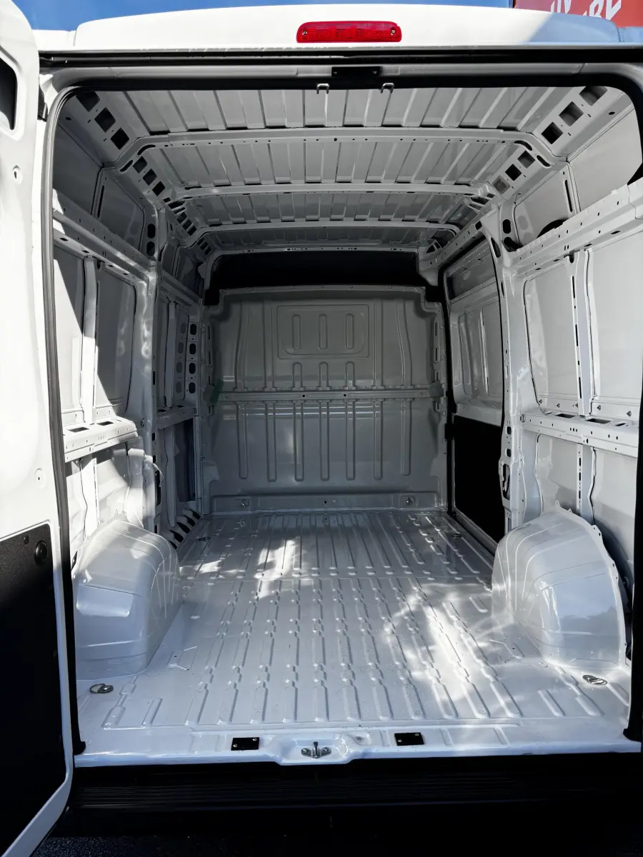 Intérieur du coffre blanc du Peugeot Boxer Fourgon L2H2 2025, vue arrière ouverte montrant l'espace de chargement vide et métallique.