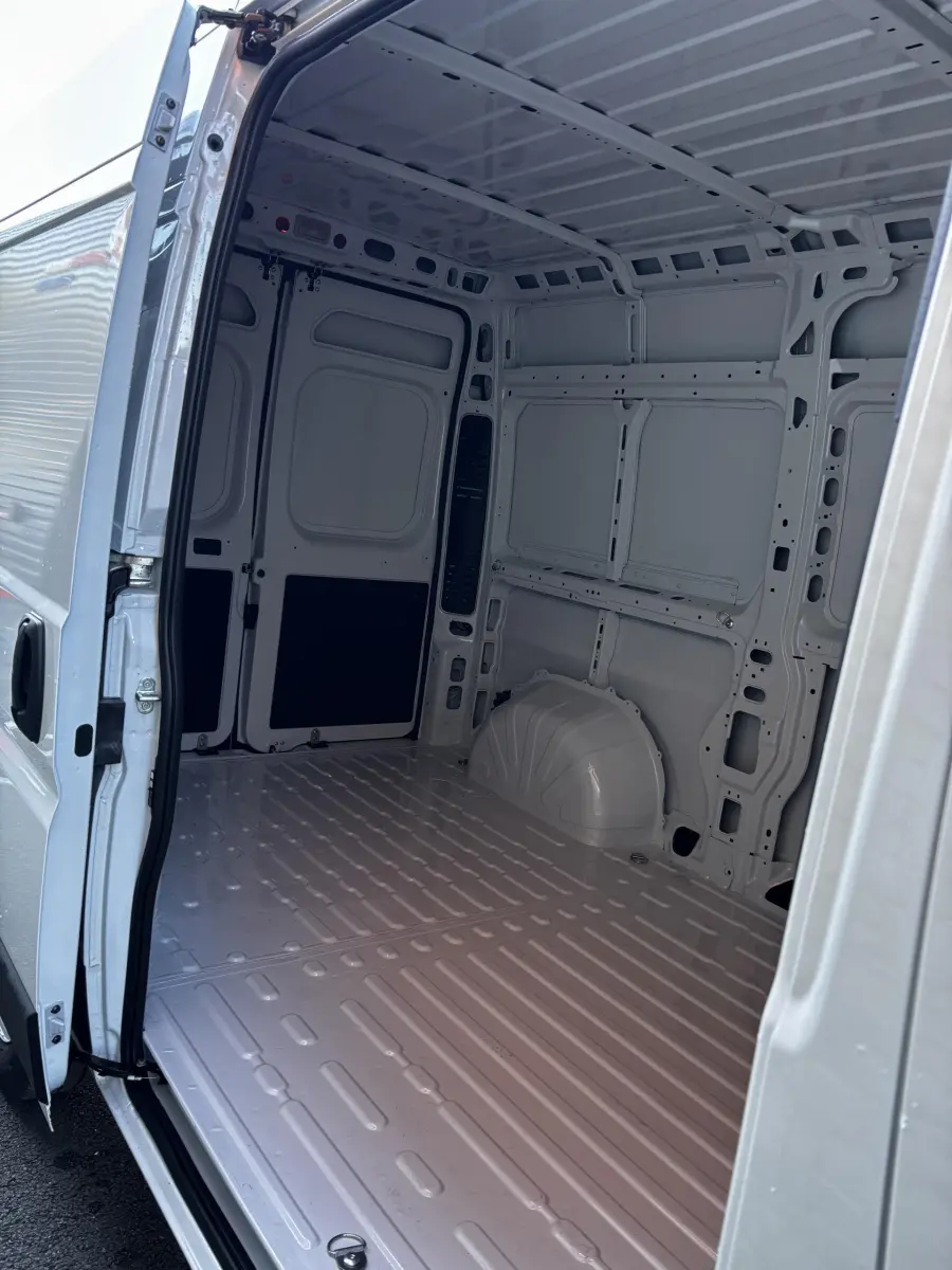 Intérieur du coffre blanc du Peugeot Boxer Fourgon L2H2 2025, vue depuis l'ouverture latérale droite.
