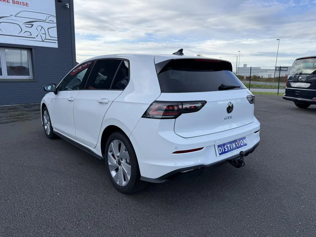 Volkswagen Golf 1.5 eHybrid blanc nacré vue 3/4 arrière droit avec attelage escamotable et vitres surteintées.