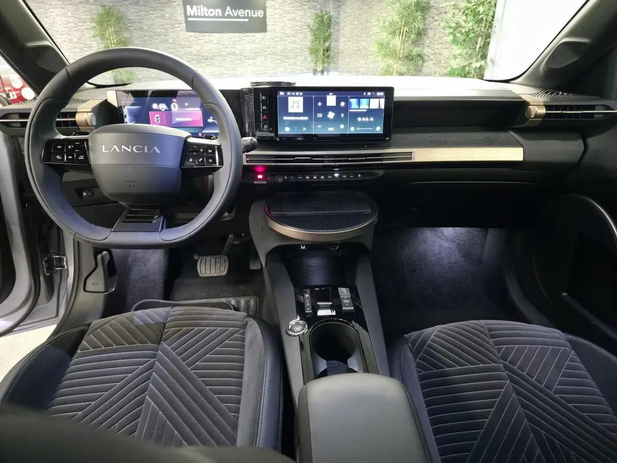 Vue intérieure frontale du tableau de bord et volant Lancia de la Ypsilon 2025 avec sellerie velours gris anthracite.