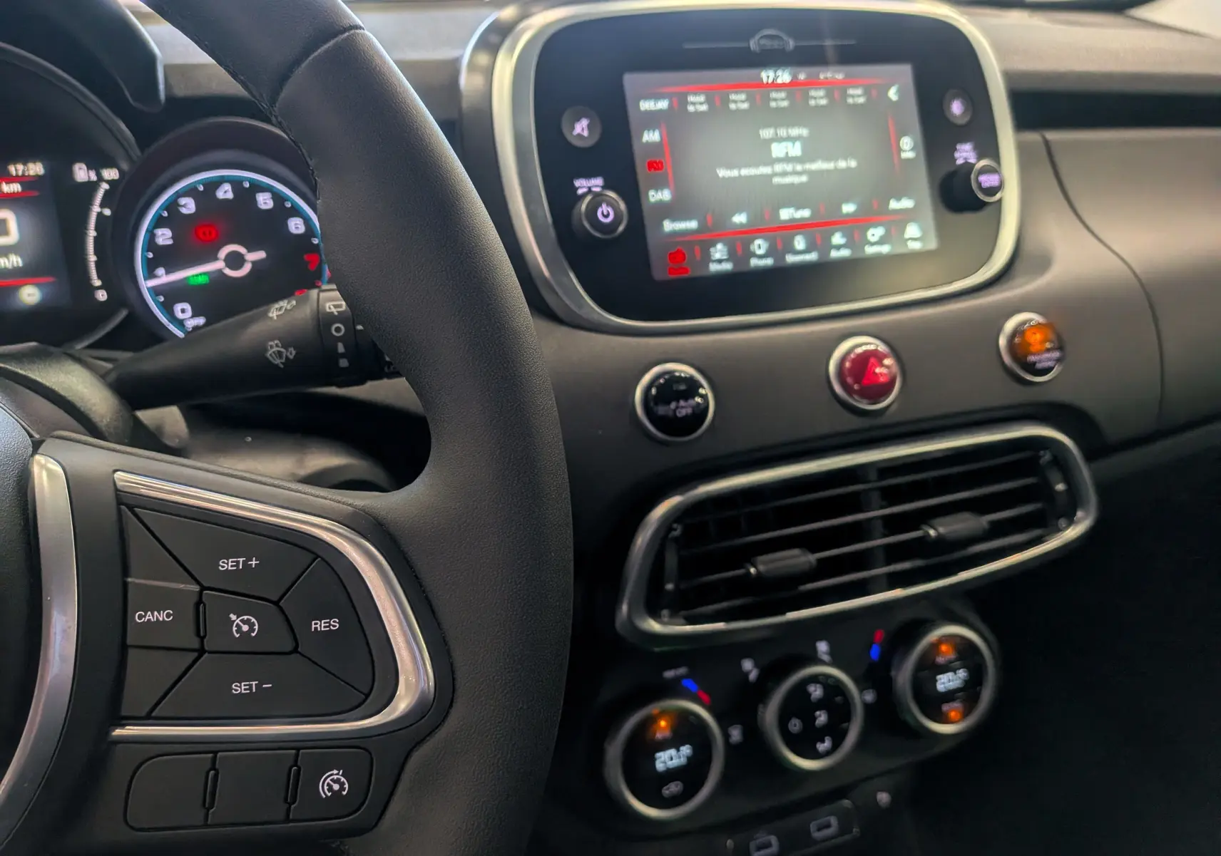 Vue intérieure centrée sur le tableau de bord et le volant noir du Fiat 500X 2024 avec écran tactile et commandes au volant.