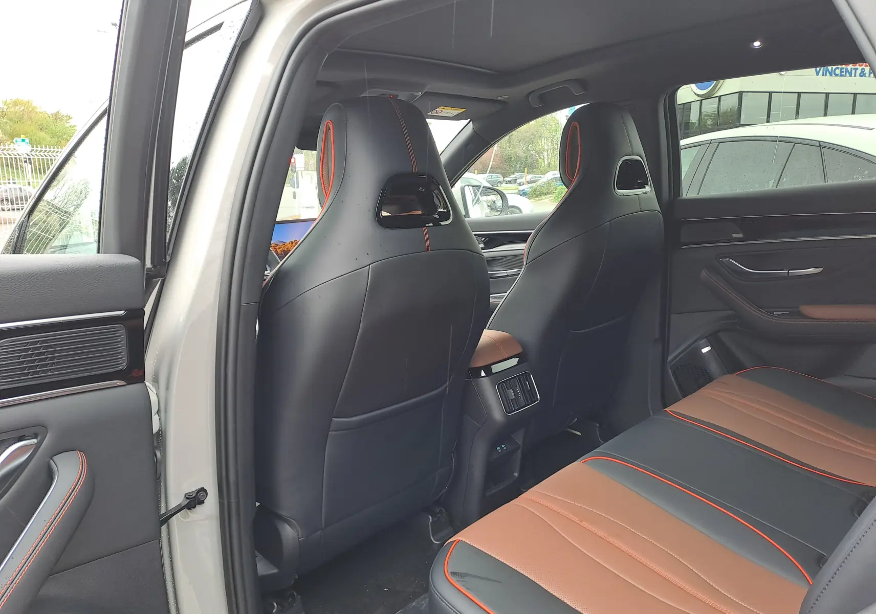 Vue intérieure arrière côté gauche du BYD SEAL U 2025 avec sièges en similicuir noir et marron à surpiqûres orange.