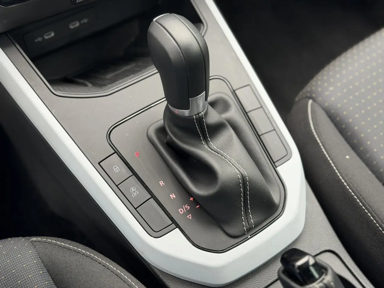 Gros plan sur la commande de boîte automatique noire et blanche du SEAT Arona TSI 115 DSG Style 2025, intérieur tissu gris.