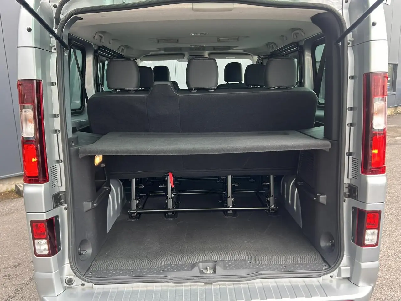 Vue arrière ouverte du Nissan Primastar gris Highland 2025, montrant l'espace de chargement et les sièges arrière.