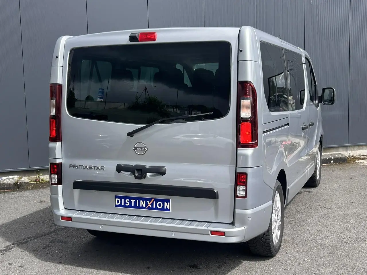 Vue 3/4 arrière droite du Nissan Primastar gris Highland avec hayon vitré et vitres latérales teintées.