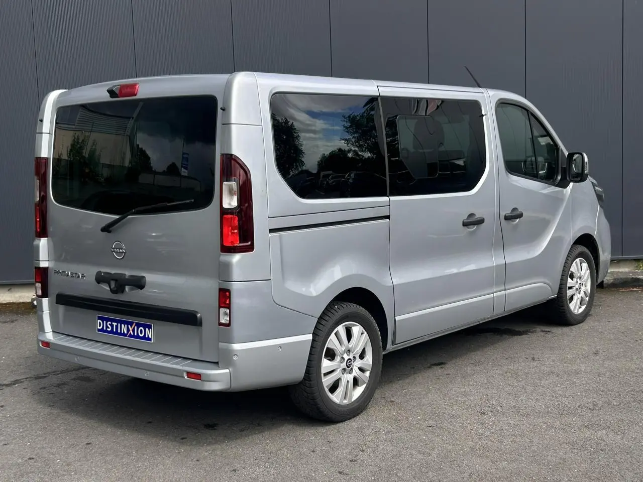 Vue 3/4 arrière droite du Nissan Primastar gris Highland avec hayon vitré et vitres surteintées.