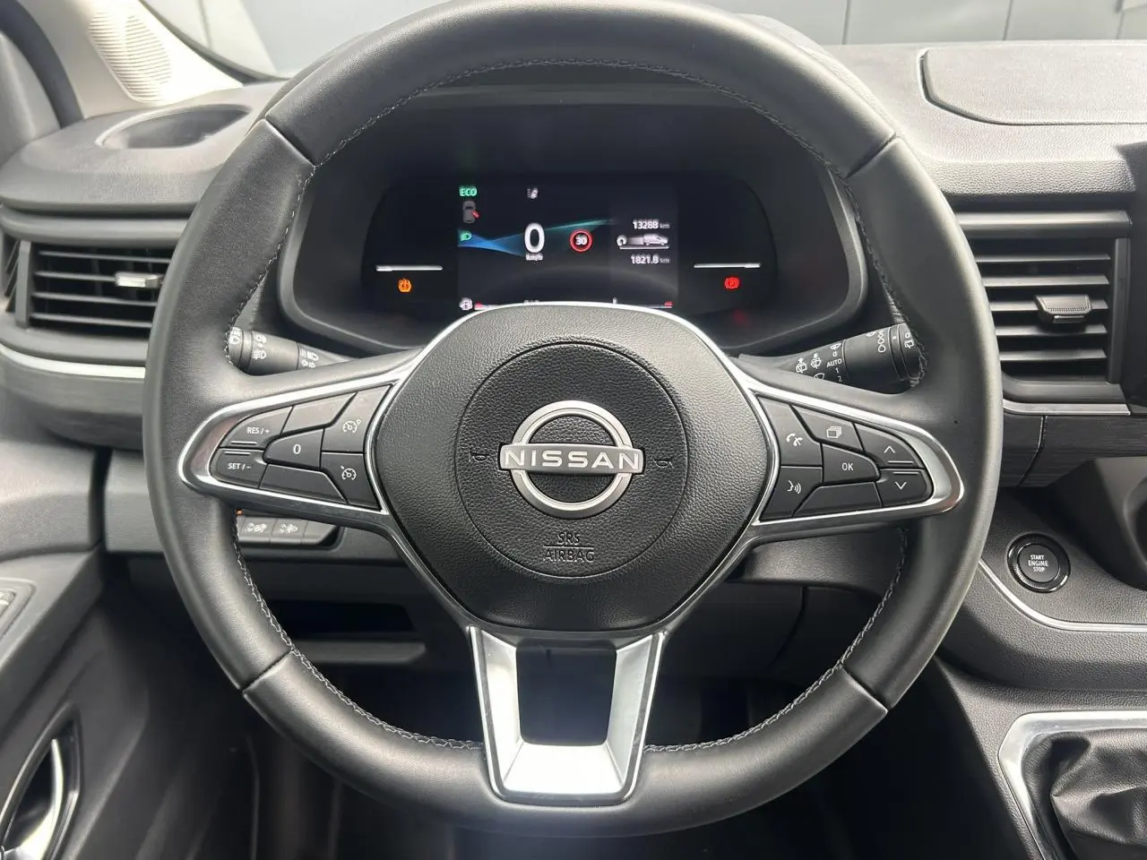 Vue centrée sur le volant noir du Nissan Primastar 2025 avec tableau de bord numérique et bouton démarrage sans clé.