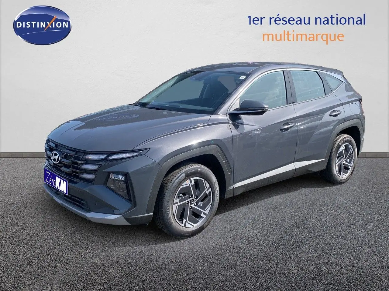 Hyundai Tucson gris Ecotronic Metal en 3/4 avant droit, SUV hybride avec jantes bi-ton et calandre marquée.
