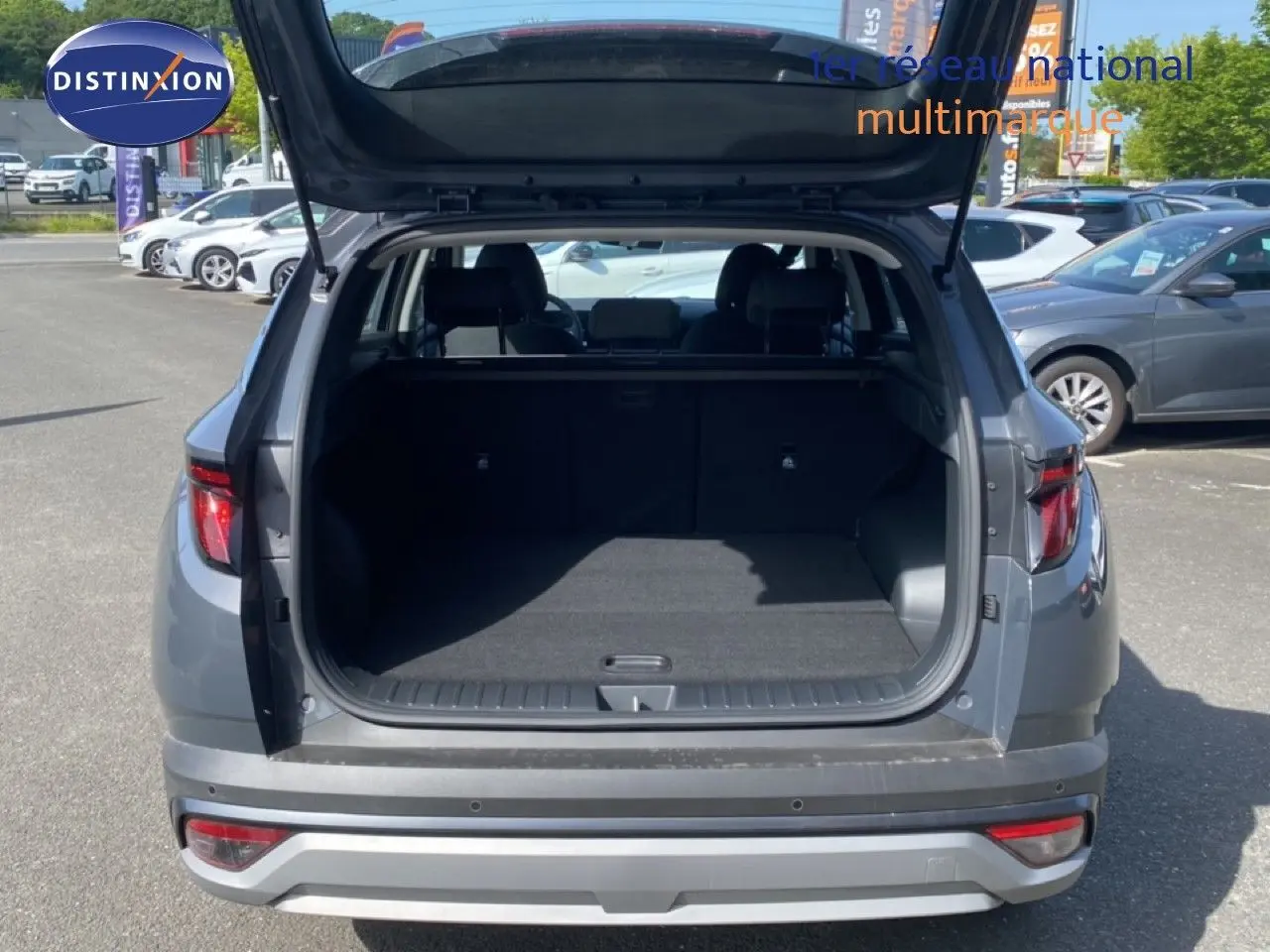 Vue arrière du Hyundai Tucson gris Ecotronic Metal 2026 avec coffre ouvert montrant l'espace de chargement vide.