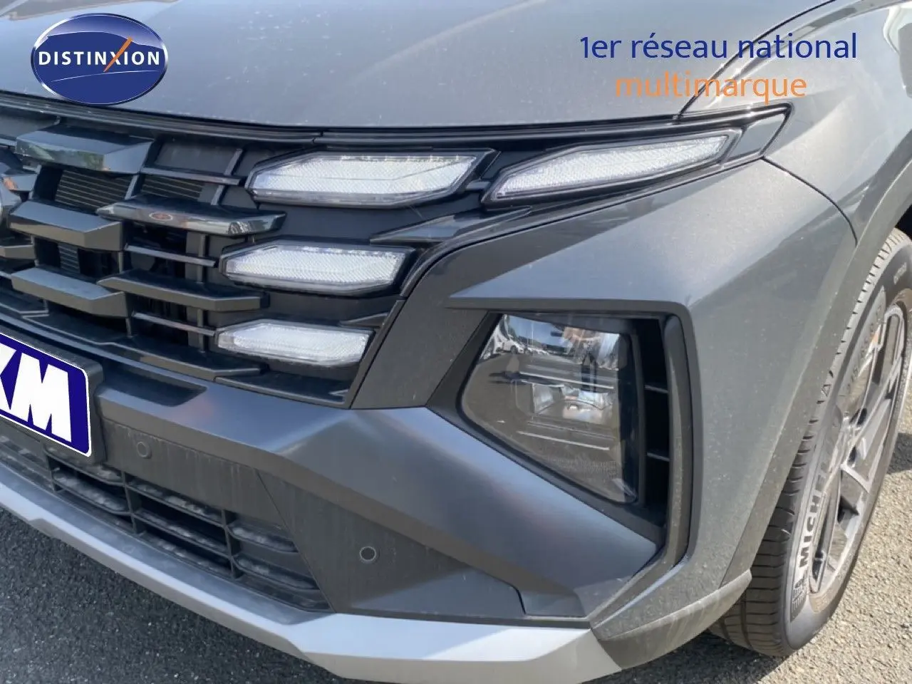 Gros plan sur l'avant droit du Hyundai Tucson gris Ecotronic Metal, mettant en valeur la calandre et les phares LED.