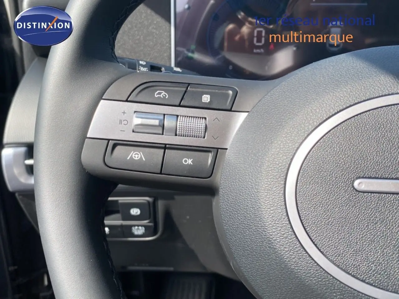 Gros plan sur le volant multifonction du Hyundai Tucson 2026 avec commandes intégrées et tableau de bord numérique flou en arrière-plan.