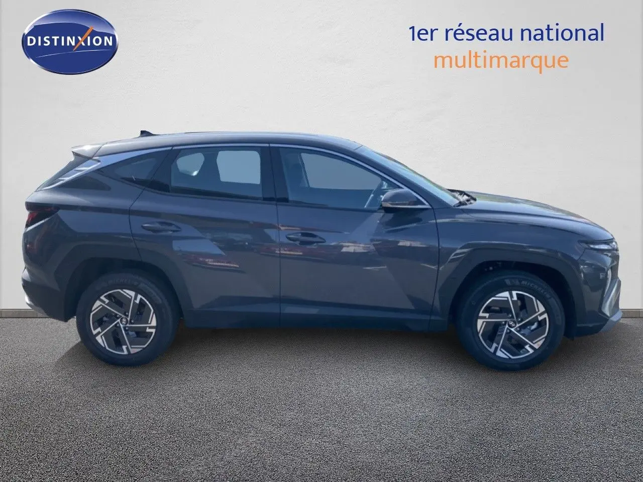 Vue de profil côté gauche du Hyundai Tucson gris Ecotronic Metal 2026 avec jantes alliage bicolores et lignes anguleuses.