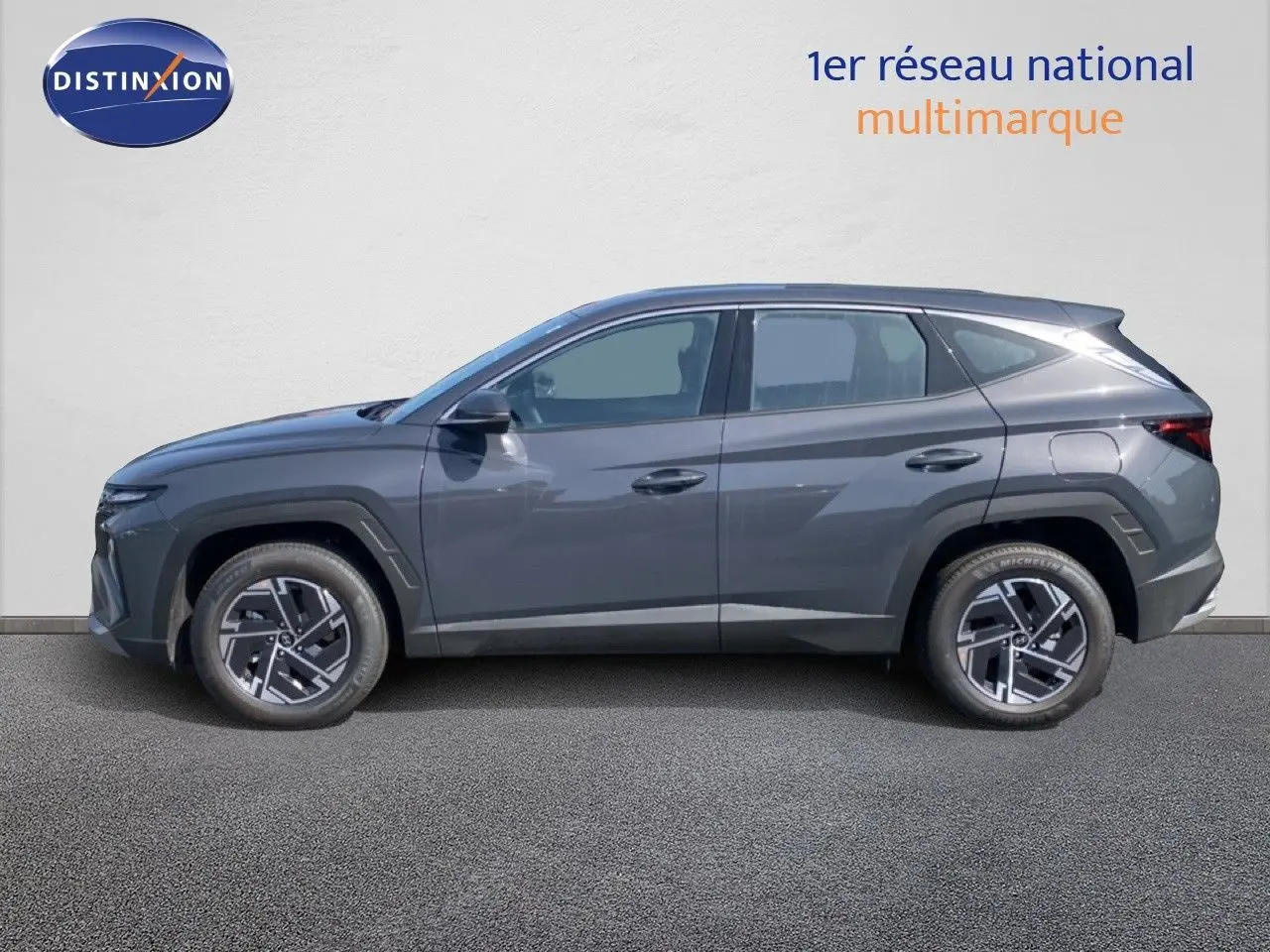 Vue de profil côté gauche d'un Hyundai Tucson gris Ecotronic Metal 2026 avec jantes bi-ton et lignes anguleuses marquées.