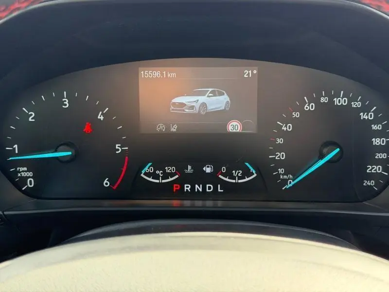 Vue rapprochée du tableau de bord numérique de la Ford Focus 2025, affichant une image du véhicule blanc et les compteurs.
