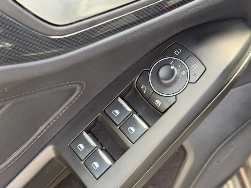 Vue rapprochée des commandes de lève-vitres et réglage des rétroviseurs côté gauche, intérieur noir de la Ford Focus 2025.