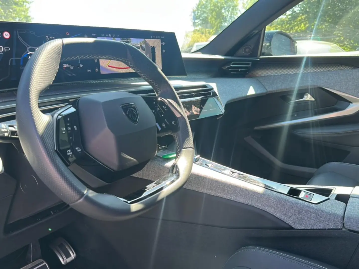 Vue intérieure côté conducteur du Peugeot 3008 gris 2025, volant cuir multifonction et écran tactile large en arrière-plan.
