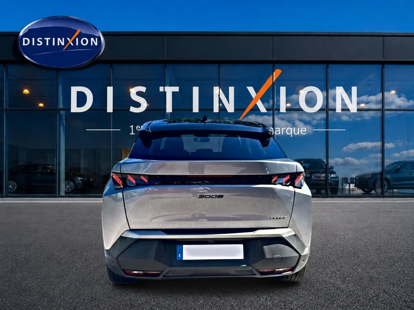 Vue arrière d'un Peugeot 3008 gris 2025 avec feux LED distinctifs et becquet arrière, devant une vitrine Distinxion.