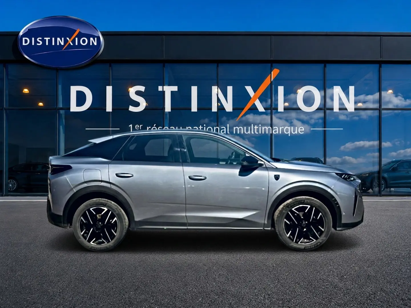 Profil côté gauche du Peugeot 3008 gris 2025 avec jantes alliage noires devant une vitrine Distinxion.