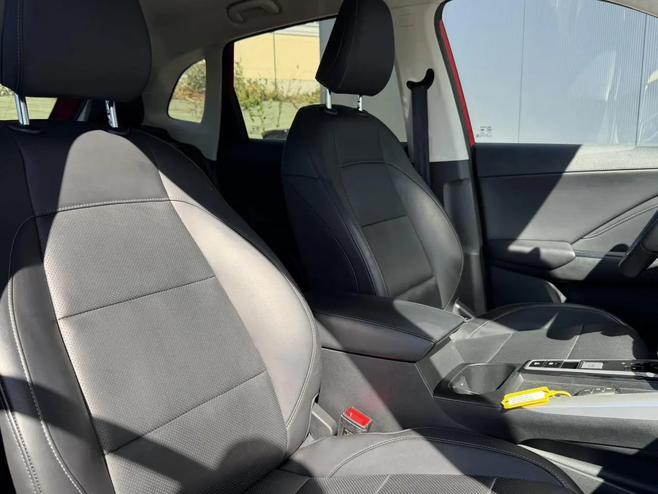 Vue intérieure côté avant droit du MG ZS 1.5 Hybrid+ 197 Luxury 2025 avec sièges tissu/similicuir noirs et accoudoir central.
