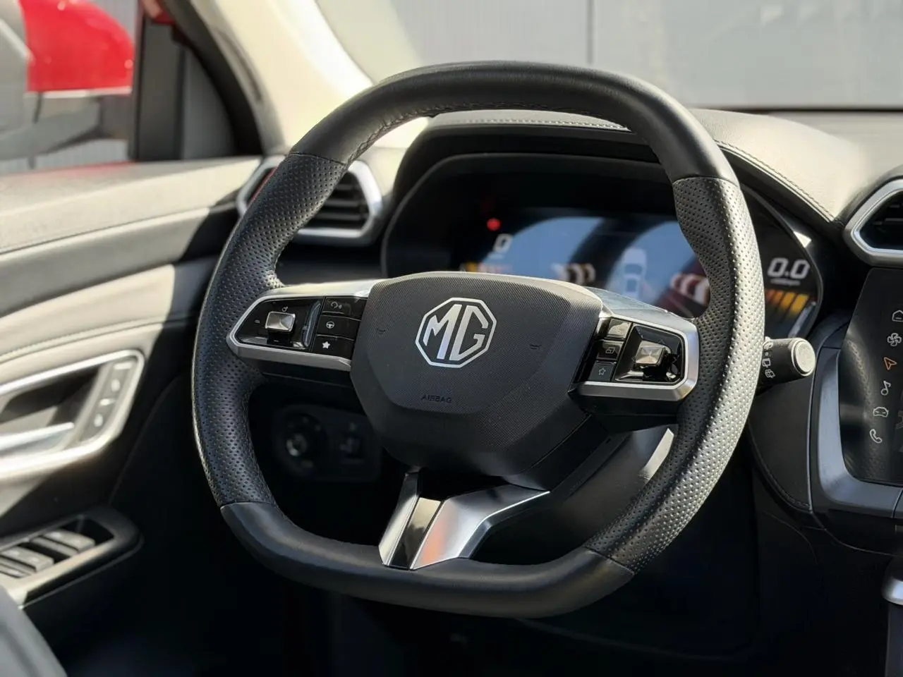 Gros plan sur le volant en cuir noir du MG ZS 1.5 Hybrid+ 197 Luxury, avec tableau de bord numérique en arrière-plan.