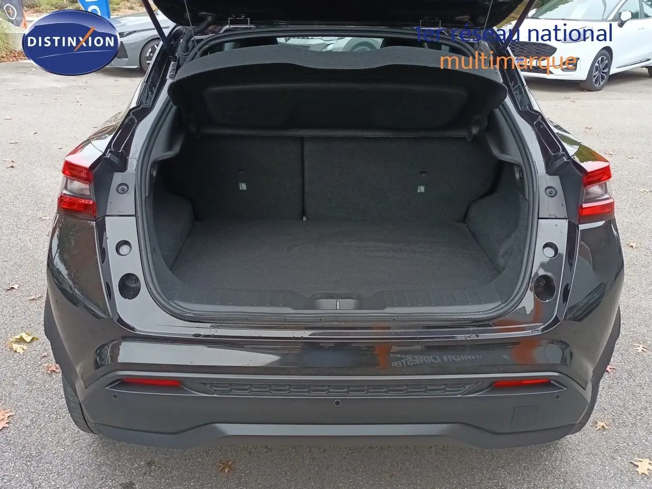 Vue arrière du coffre ouvert d'un Nissan Juke Hybrid 143ch Business+ noir métal, montrant l'espace de chargement vide.