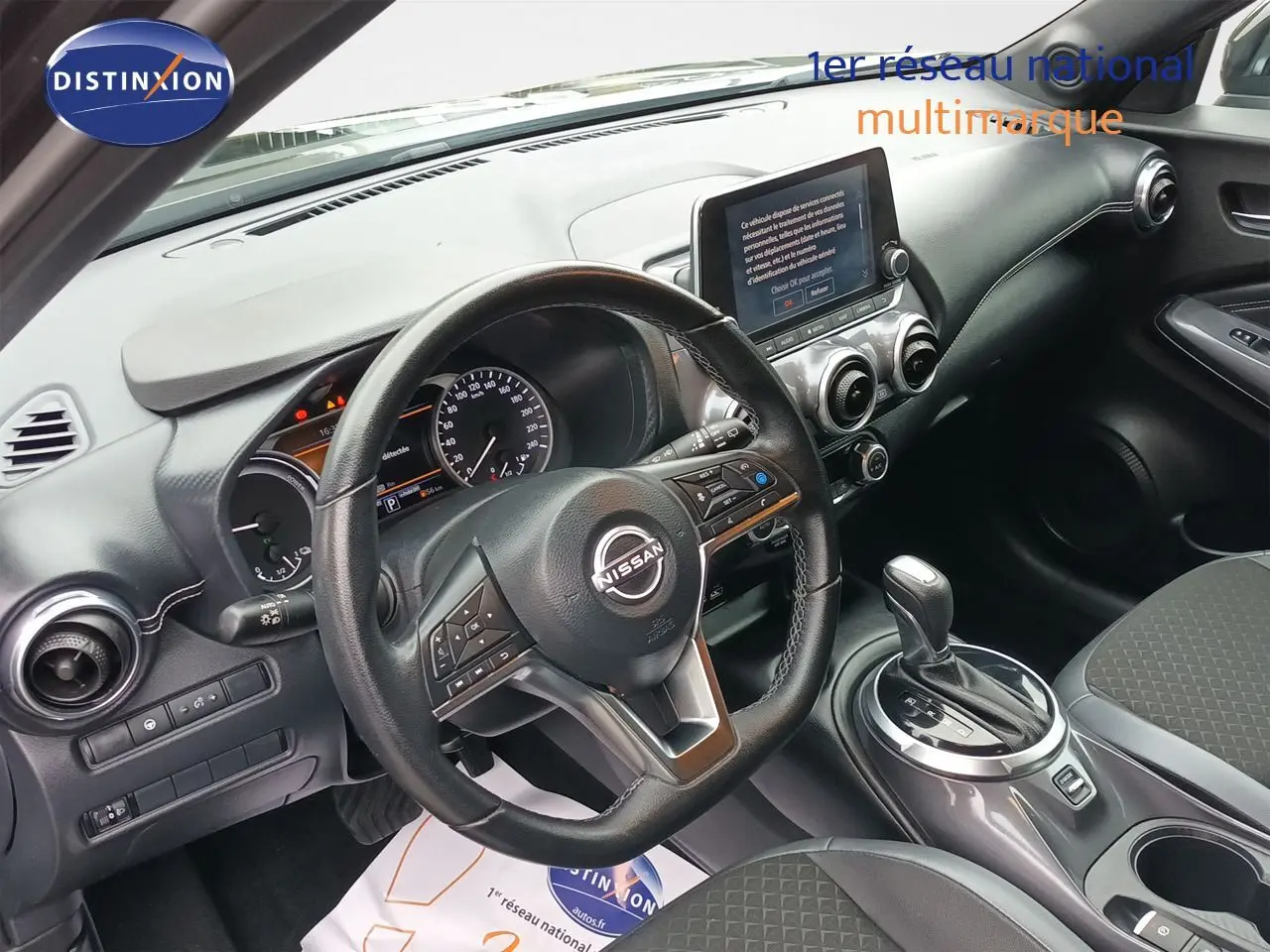 Vue intérieure côté conducteur du Nissan Juke Hybrid 2024 noir métal, avec tableau de bord et écran tactile central.