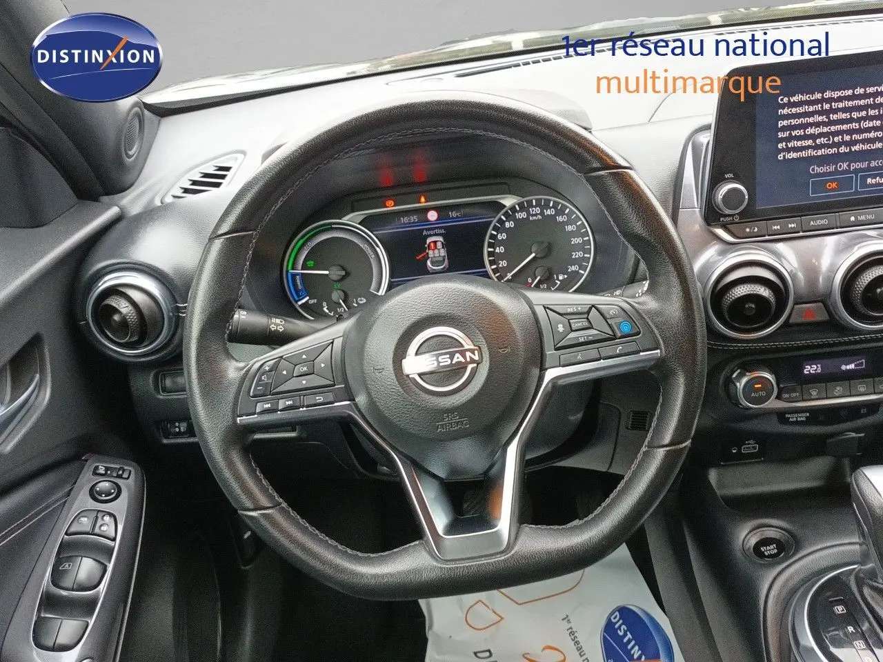 Vue intérieure centrée sur le volant cuir noir du Nissan Juke Hybrid 2024 avec tableau de bord et écran tactile.