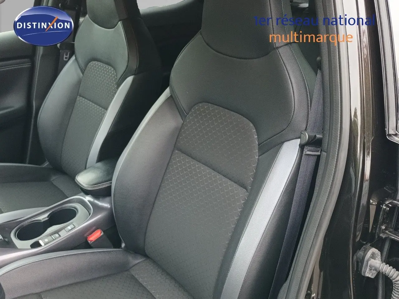 Vue intérieure sur les sièges avant en tissu noir et cuir d’un Nissan Juke Hybrid 2024, porte côté droit ouverte.