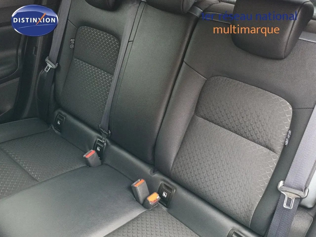 Vue rapprochée des sièges arrière noirs en tissu texturé du Nissan Juke Hybrid 2024, avec ceintures de sécurité visibles.