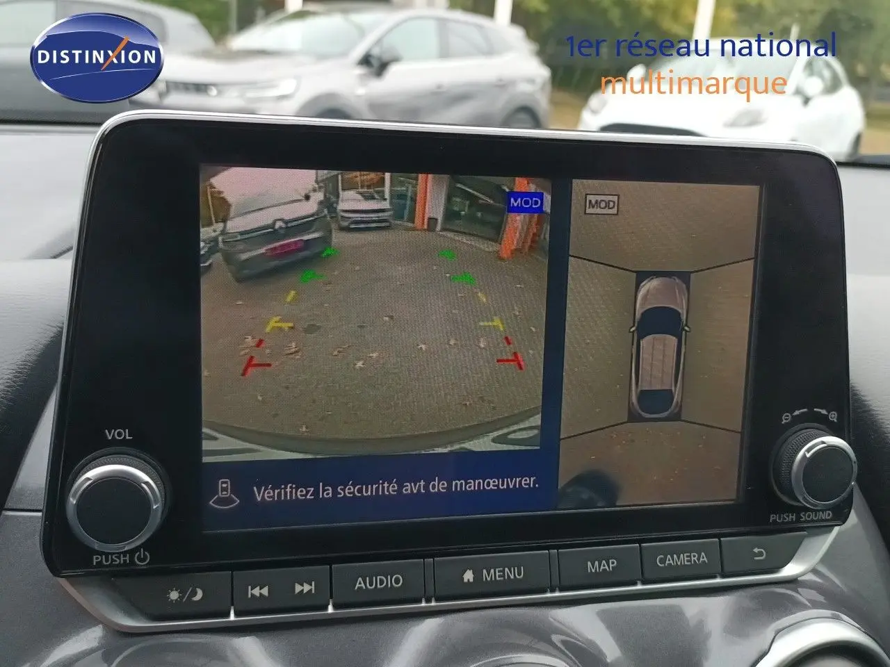 Écran multimédia montrant la caméra de recul et vue 360° du Nissan Juke noir métal, intérieur avec commandes visibles.