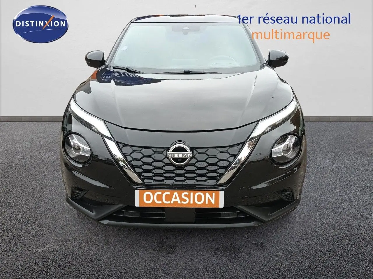 Vue frontale d'un Nissan Juke Hybrid 143ch Business+ noir métal avec calandre en nid d'abeille et phares ronds distinctifs.